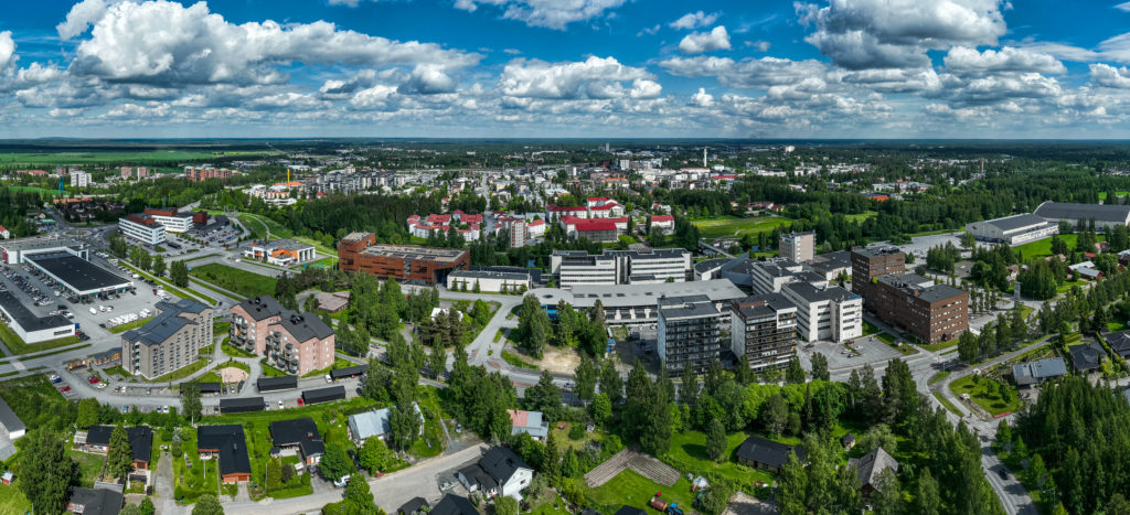 Viistoilmakuva Seinäjoen keskustasta. Kuvassa erottuu rakennuksia, vehreyttä , teitä ja poutapilvinen taivas.