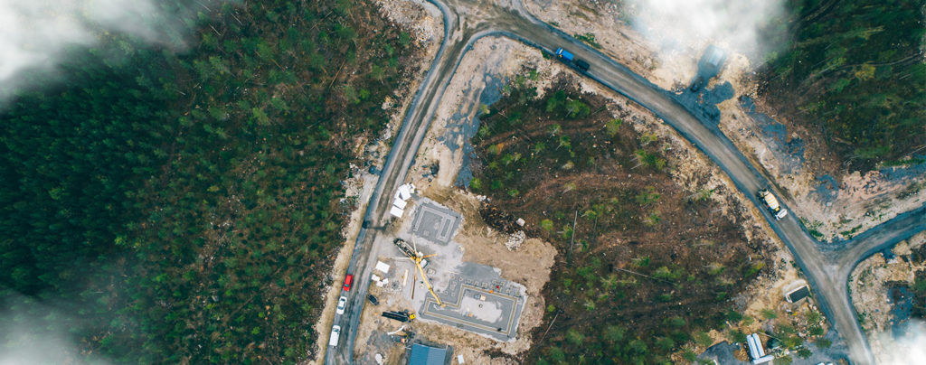 Construction site of a detached house plot photographed from above. Fluffy clouds are also visible.