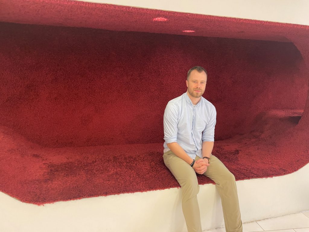 Mies istuu punaisessa seinään upotetussa lukukolossa.