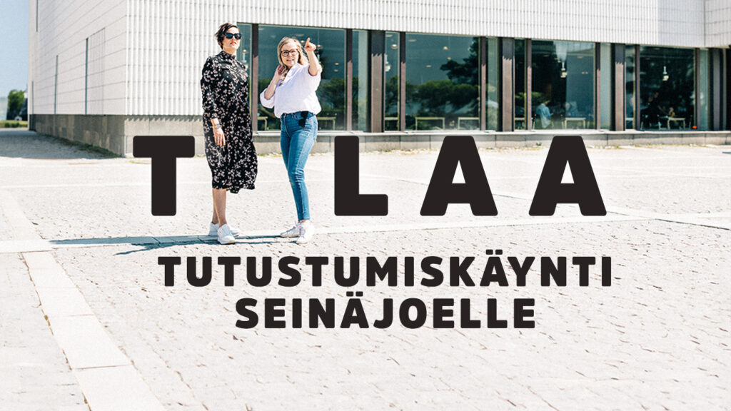 Naiset seisova Tilaa tutustumiskäynti Seinäjoelle -tekstin keskellä.