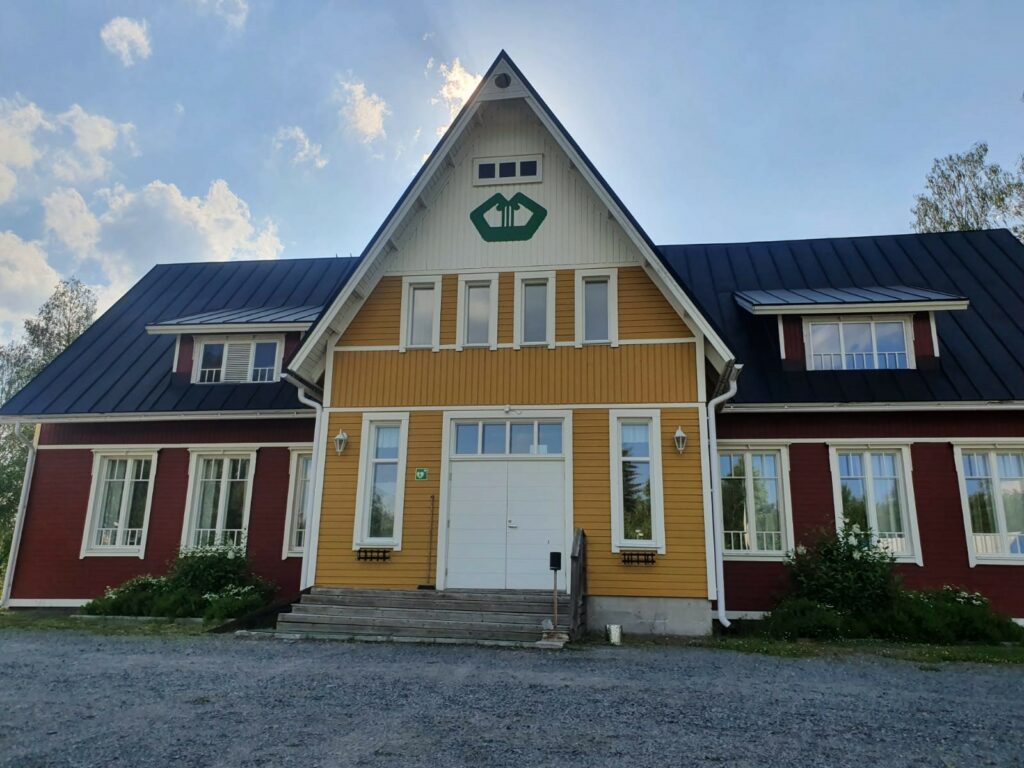 Punainen vanha puutalo, jossa keltainen iso sisääntulokuisti.