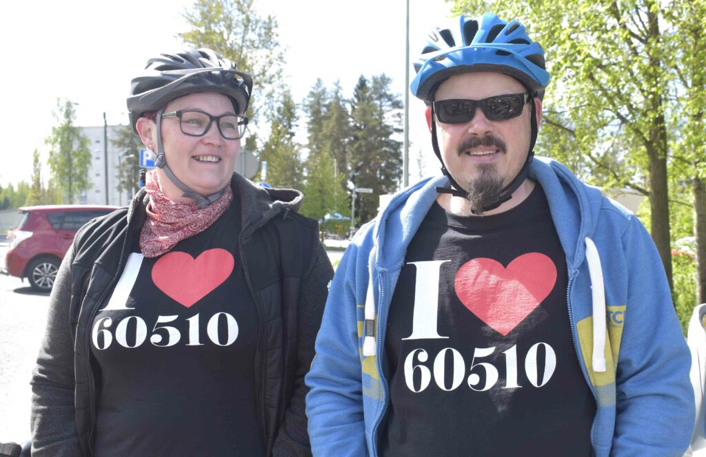 Nainen ja mies pyöräilykypärät päissään esittelevät päällään olevia paitoja, joissa lukee "I sydän 60510".