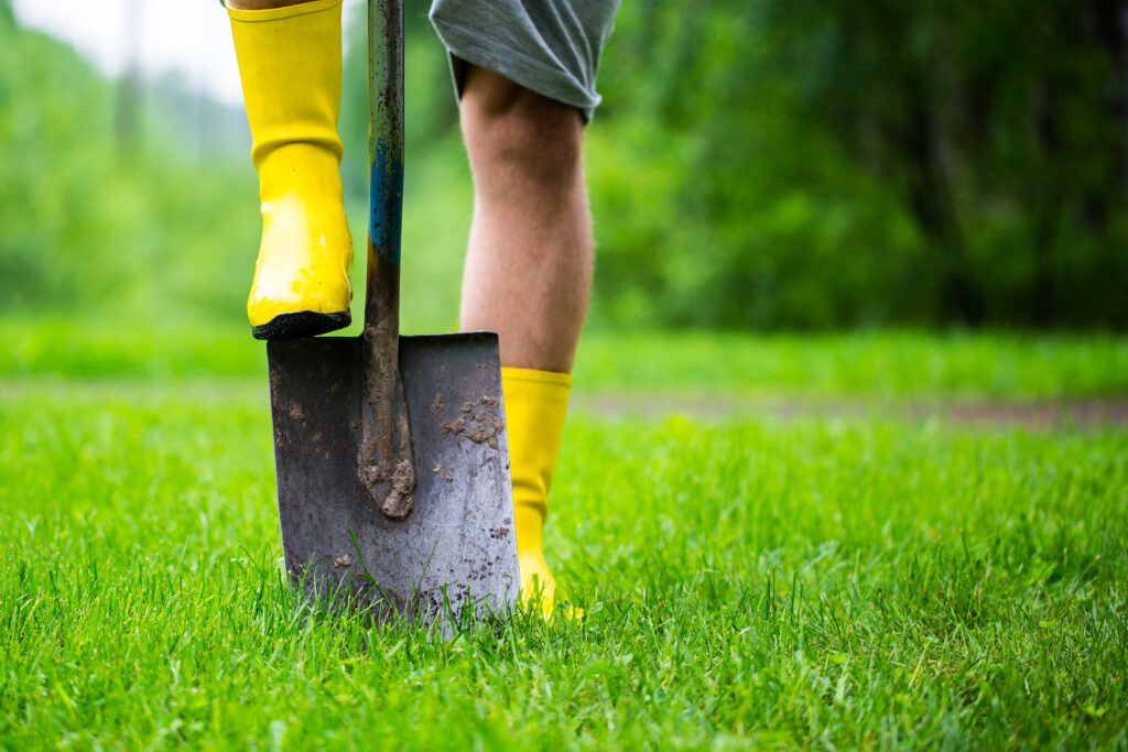 Keltaiset saapasjalat vihreällä nurmella. Toinen saapasjalka on rautalapion päällä.