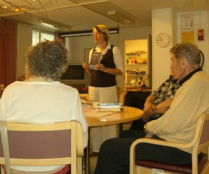 Kirjaston työntekijä Jaana Savela vinkkaamassa ja kolme senioria kuuntelee.