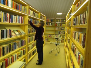 Kirjaston työntekijä hyllyttää aikuisten kirjasalissa palautettuja kirjoja.