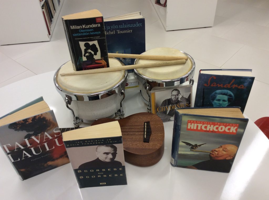Pirjon, Päivin ja Jarkon suosikkikirjoja pöydällä. Pöydällä myös rekvisiittana ukulele ja bongorummut.