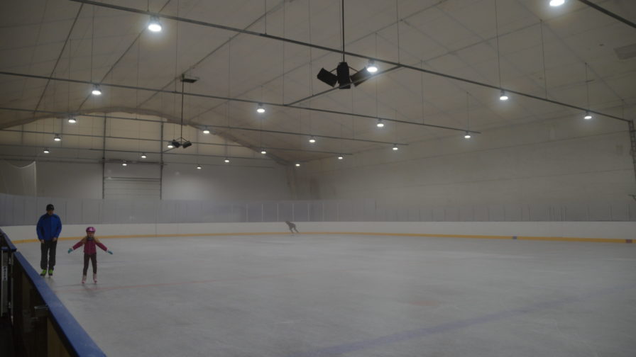 Kuvassa harjoitusjäähallin kaukalo ja kolme luistelijaa.
