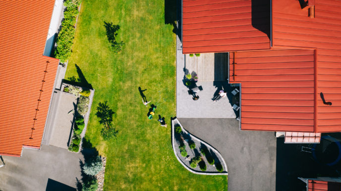 Ilmakuva omakotitalon pihasta. Punainen katto, vihreä nurmikko.