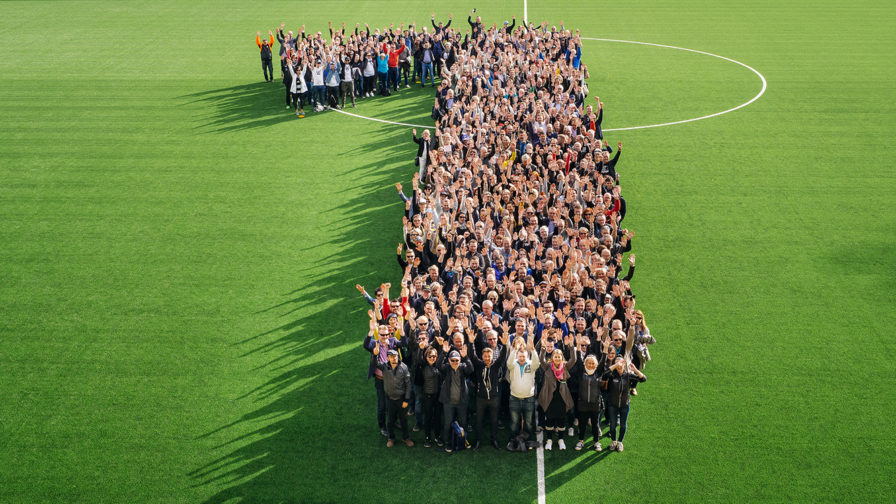 Ihmisjoukosta koostettu iso numero 1 jalkapallostadionin vihreriöllä.