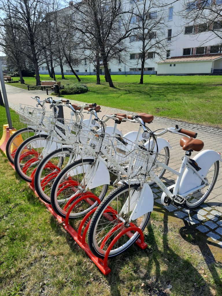 Valkoisia kaupunkipyöriä punaisessa pyörätelineessä.