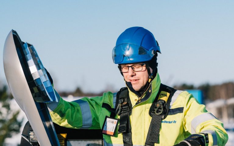 Suojavarusteisiin ja kypärään sonnustautunut henkilö korjaa katuvaloa kurottajassa.