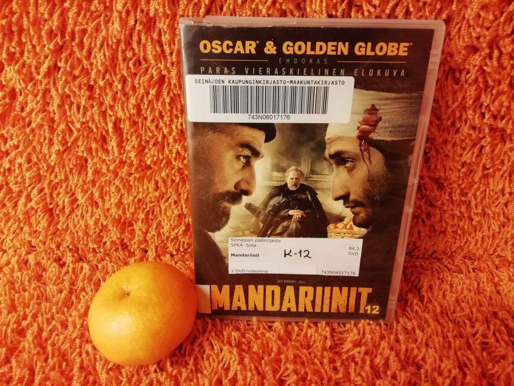 Elokuvan kansi oranssilla taustalla, vieressään mandariini.
