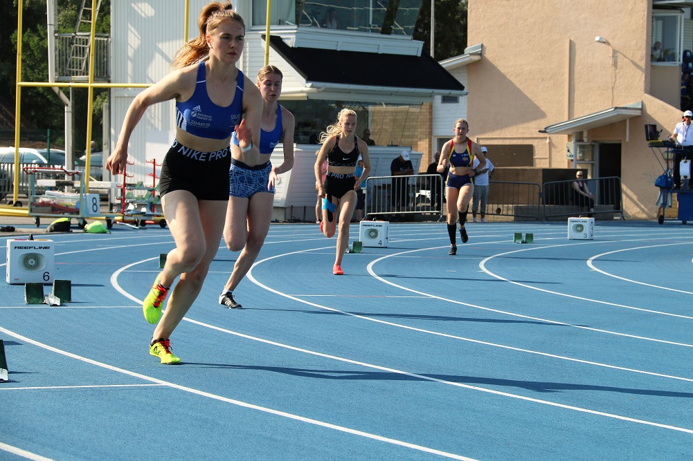 Kuvassa urheilijoita juoksemassa sinisellä urheilukentällä.