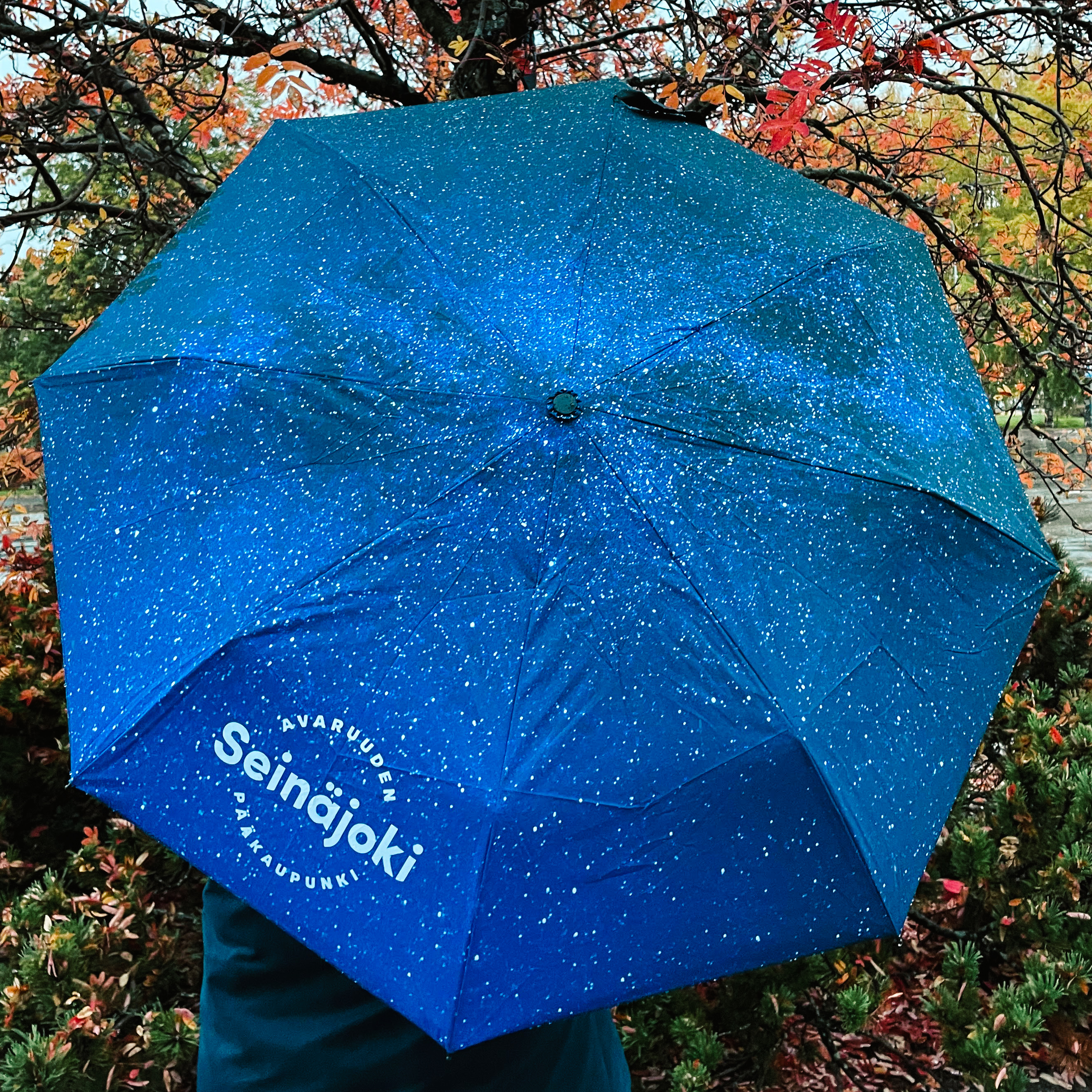 Sininen tähtitaivaskuvioinen sateenvarjo avattuna.