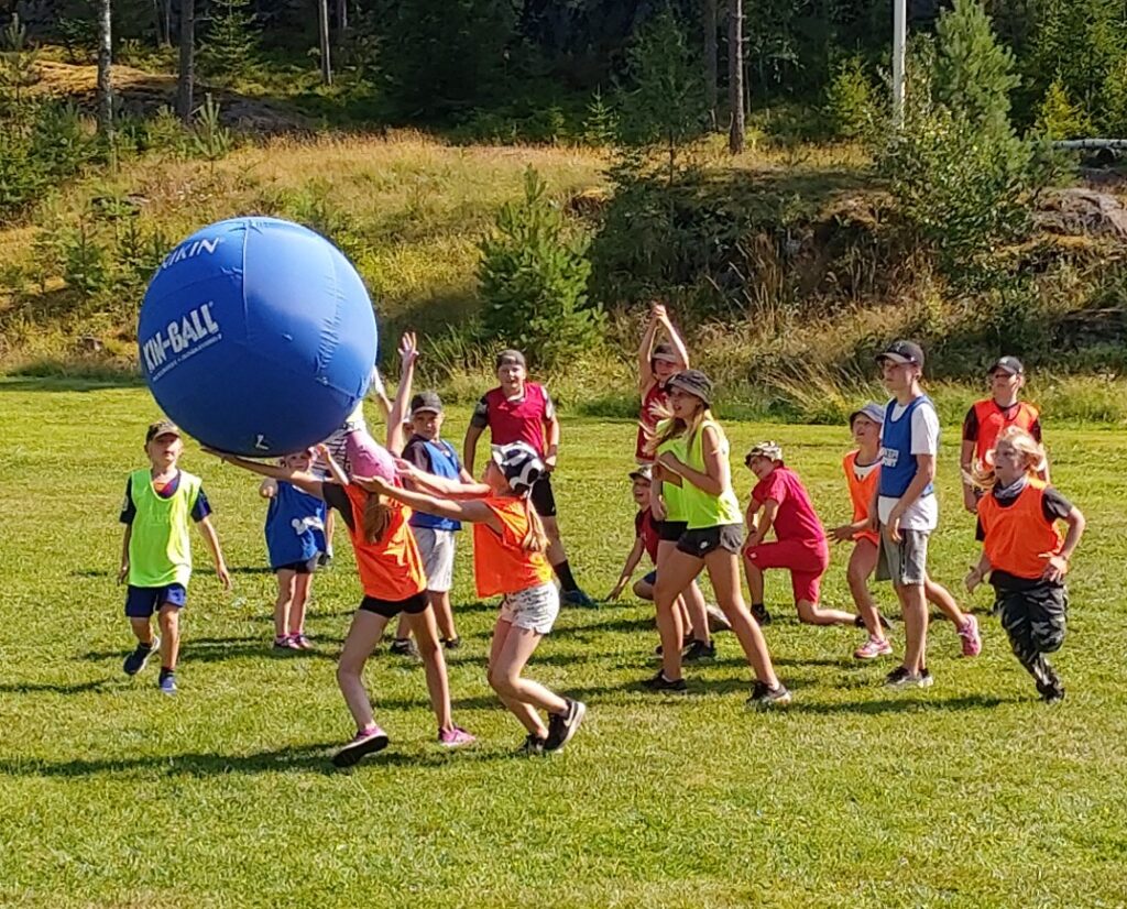 Kuvassa lapsia pelaamassa sinisellä Kin-ball pallolla nurmikolla.