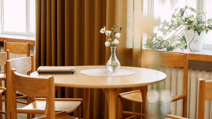 kahvilatila, pöytä, tuoleja ja kukkamaljakko pöydällä