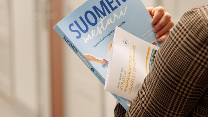 henkilö pitää oppikirjaa