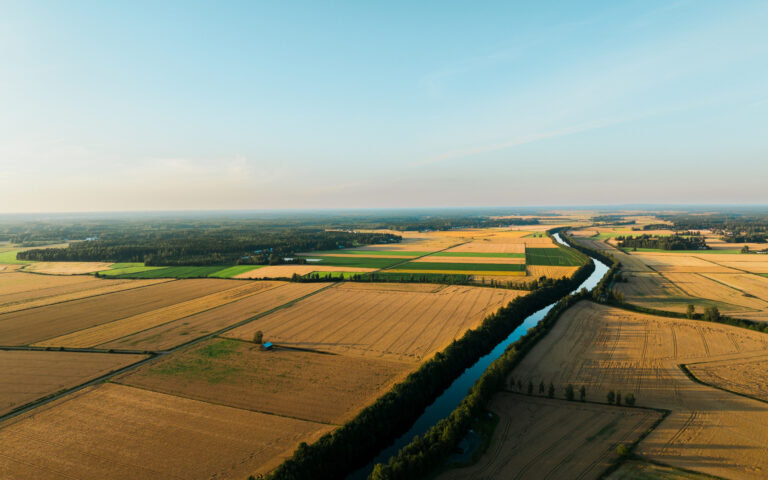 Avara peltomaisema, jonka poikki kulkee joki.