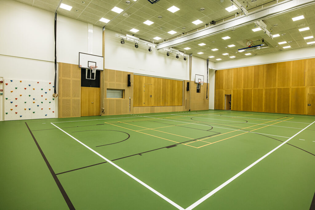 Kärjen koulun liikuntahalli. Palloilukenttä edustalla, takana näkyy kiipeilyseinä ja koripalloteline.