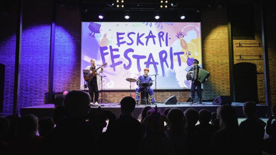 Kuvassa orkesteri esiintyy esiintymislavalla esiintymisvalojen loisteessa.