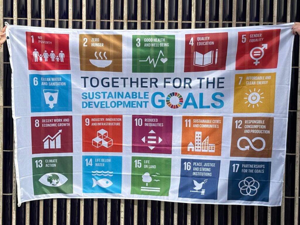 Kestävän kehityksen lippu, jossa on kuvattu Agenda 2030 17 tavoitetta: ei köyhyyttä, eikä nälkää, hyvää terveyttä ja hyvinvointia, hyvä koulutus, sukupuolten tasa-arvo, puhdas vesi ja sanitaatio, edullinen ja puhdas energia, ihmisarvoista työtä ja talouskasvua, kestävää teollisuutta, innovaatioita ja infrastruktuureja, eriarvoisuuden vähentäminen, kestävät kaupungit ja yhteisöt, vastuullista kuluttamista, ilmastotekoja, vedenalainen elämä, maanpäällinen elämä, rauha oikeudenmukaisuus ja hyvä hallinto, yhteistyö ja kumppanuus