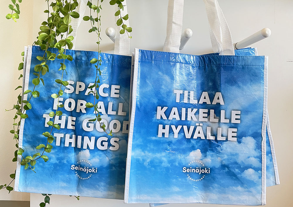 Kaksi sinistä pilvikuvioista kassia, joissa valkoista tekstiä: Tilaa kaikelle hyvälle, Space for all the good things.