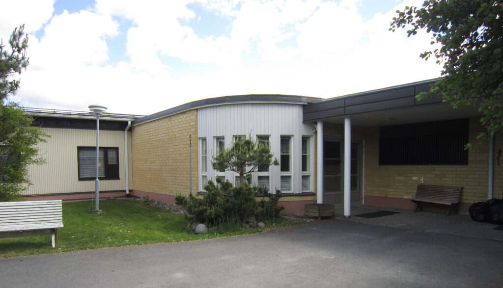 Sisäänkäynnin vieressä on kaareva osa, jossa on kapeat pystyt ikkunat. 