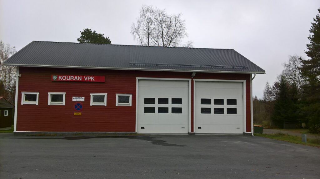 Kouran Palotalli, punainen rakennus, jossa on kaksi isoa valkoista nosto-ovea paloautoille. 