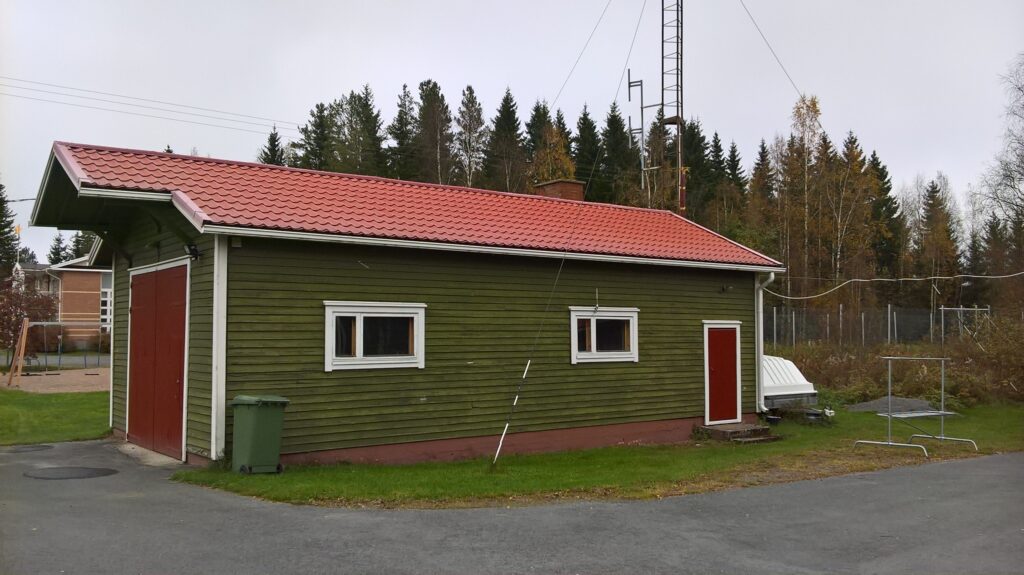 Palotallin varastorakennus, jossa on vihreät seinät ja punainen katto.