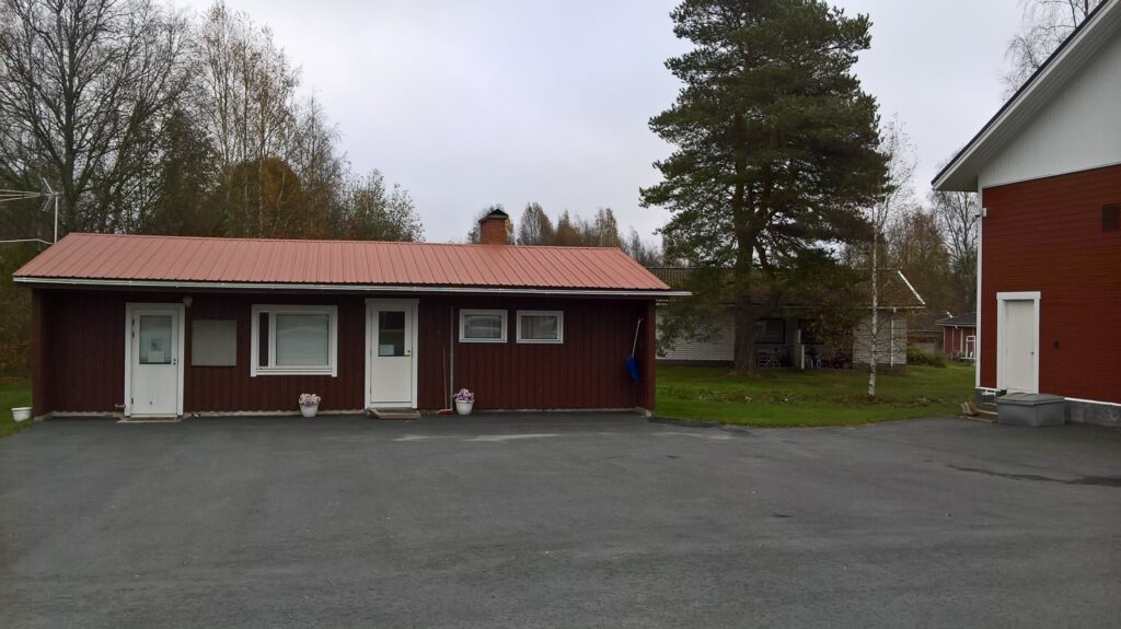 Paloaseman virkistystilan on pieni matala rakennus, jossa on tummat seinät ja valkoiset ovet. 