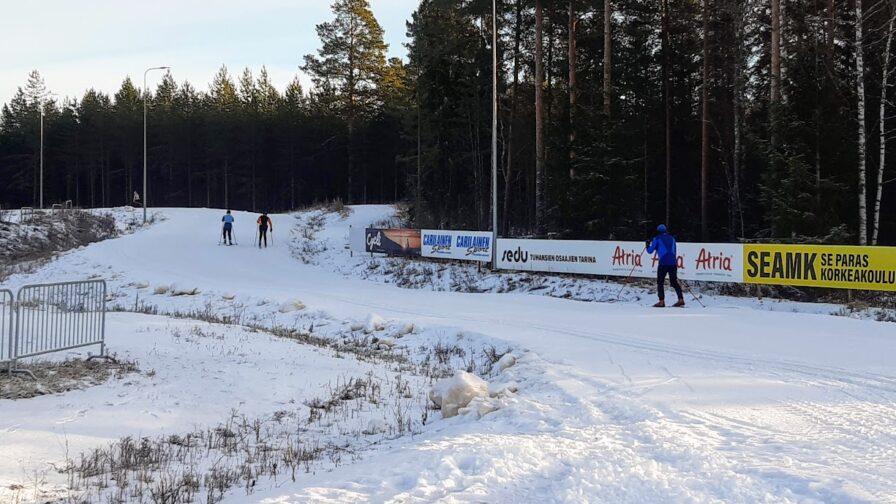 Aurinkoisella hiihtoladulla hiihtäjiä.