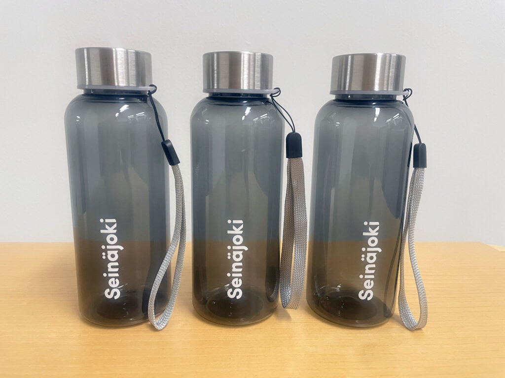 Kolme harmaata pulloa pöydällä. Pulloissa lukee valkoisella Seinäjoki.