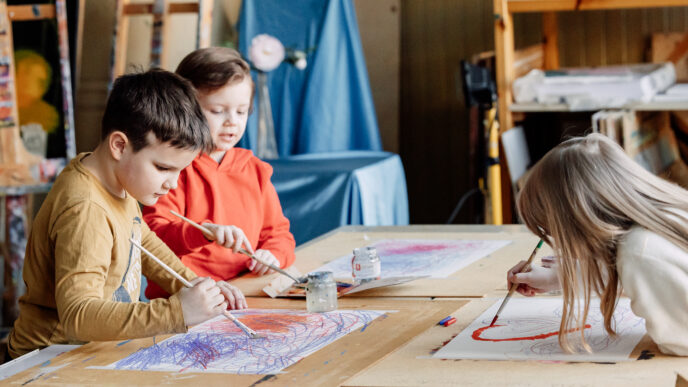 kolme nuorta henkilöä maalaa vesiväreillä