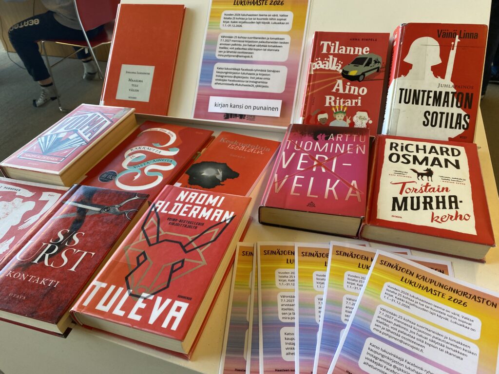 Punakantisia kirjoja ja värikkäitä lukuhaastevihkoja.