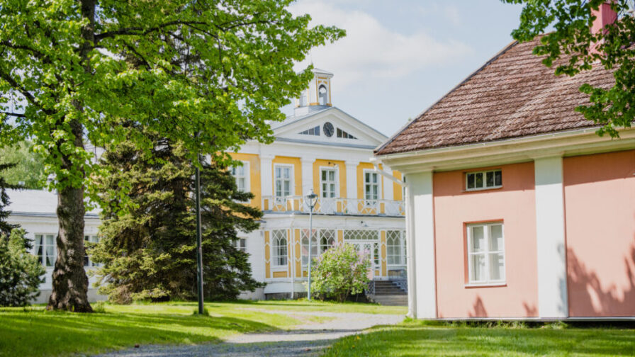 Törnävän kartano, edestä. Edessä punatulkku rakennuksen sivu ja iso puu.