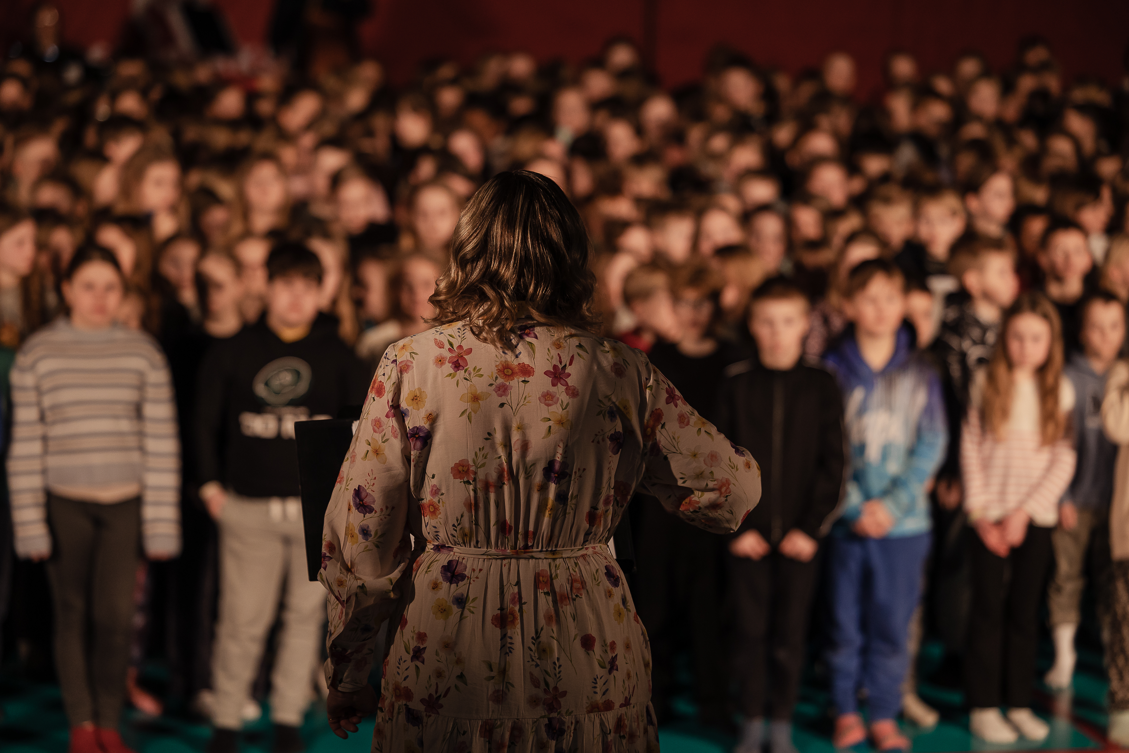 Lasten suurkuoro laulaa kuoronjohtajan johdolla.