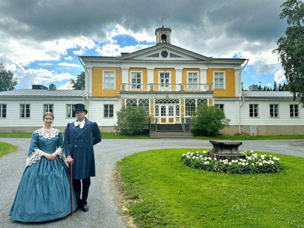 Mies ja nainen 1800-luvun vaatteissa Törnävän kartanon edessä. 