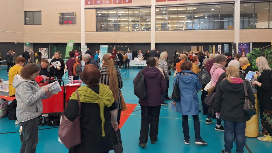 Ihmisiä kiertelemässä esittelypisteillä palloilusalissa.