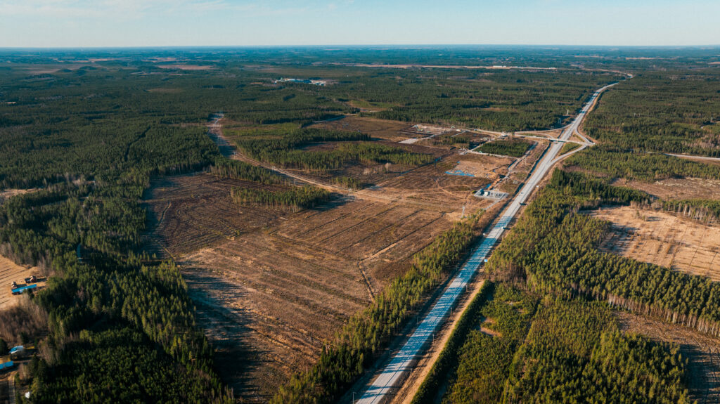 Ilmakuva isosta maastossa sijaisevasta puuttomasta tontista teiden risteyksessä