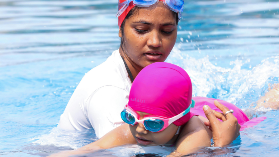 Aikuinen kannattelee lasta vedessä.