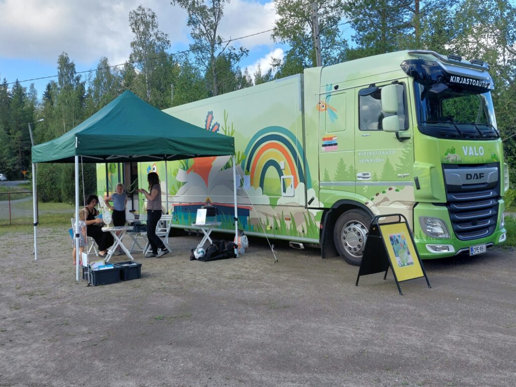 Pääsävyltään vihreä kirjastoauto hiekkakentällä. 