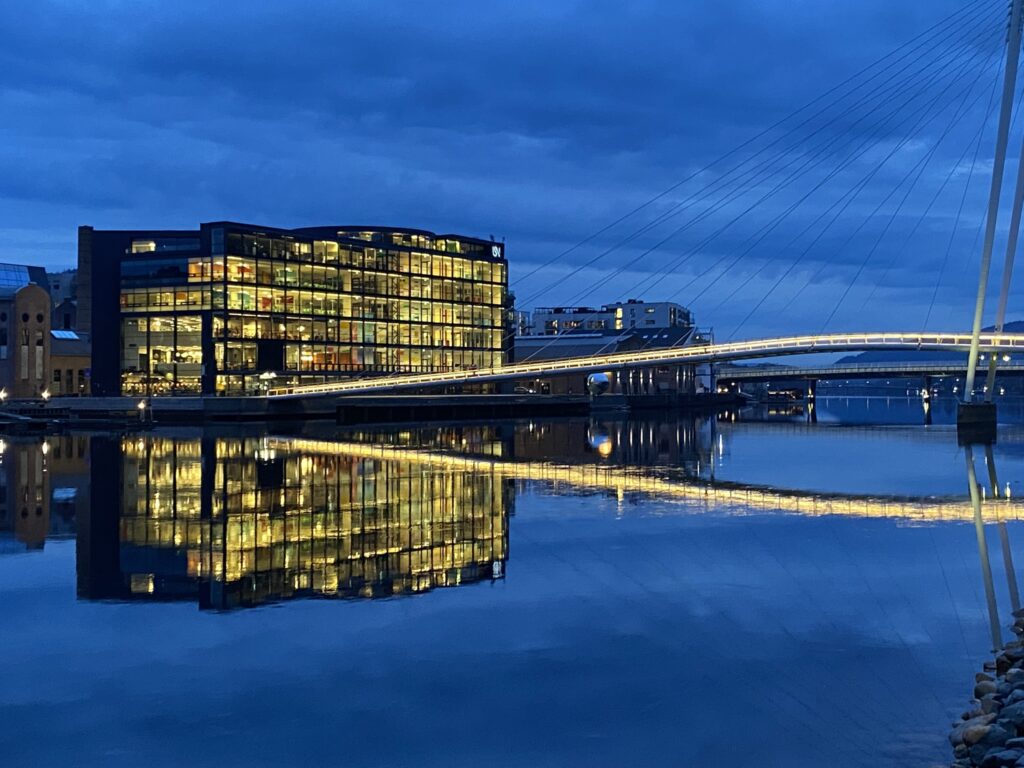 Valaistu rakennus ja silta joen varrella.