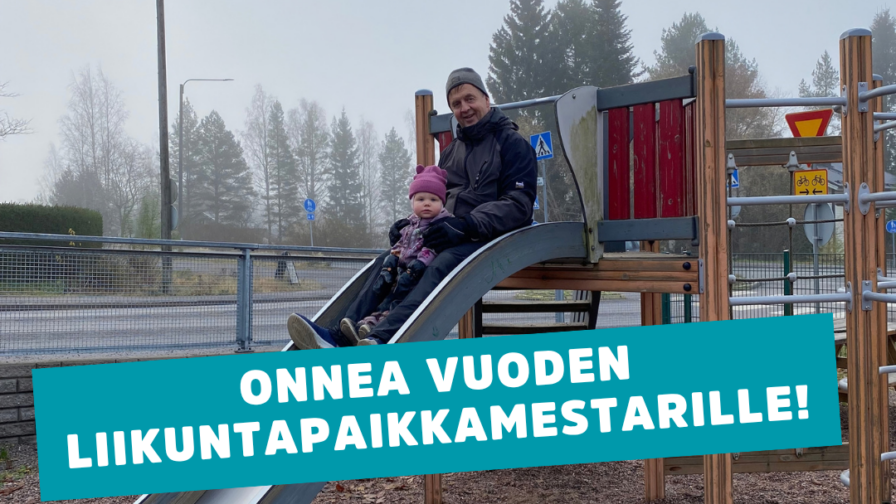 Aikuinen ja lapsi leikkitelineen liukumäessä.